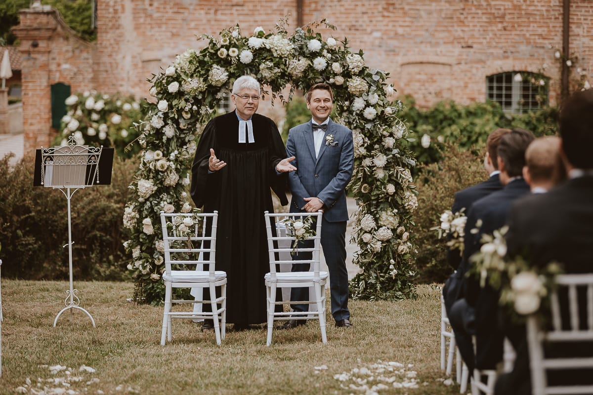 Destination wedding al Relais Sant'Uffizio. Cerimonia.Sposo aspetta la sposa e conversa con il pastore protestante.