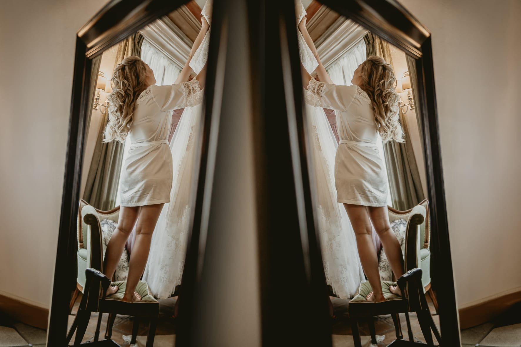 Destination wedding al Relais Sant'Uffizio. Preparazione della sposa. Sposa che prende il suo abito, riflessa nello specchio.