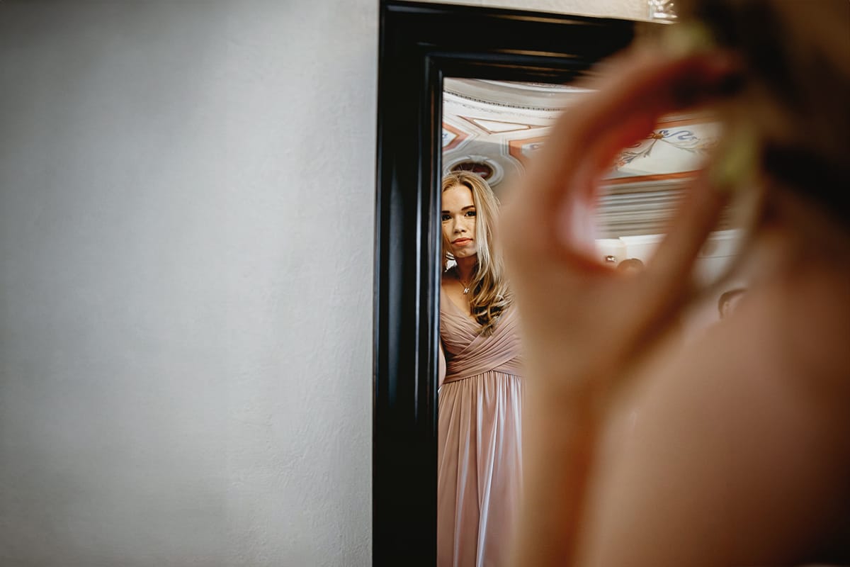 Destination wedding al Relais Sant'Uffizio. Preparazione della sposa. Damigella si guarda allo specchio