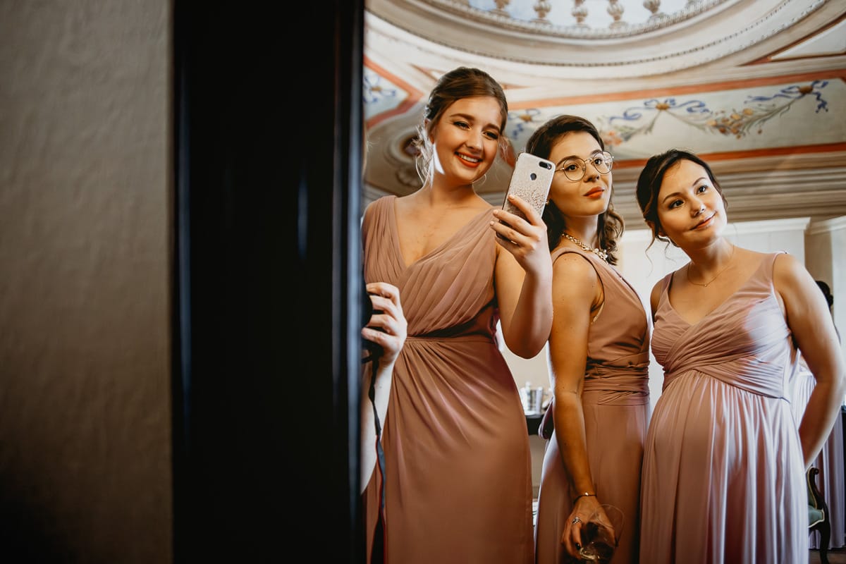 Destination wedding al Relais Sant'Uffizio. Preparazione della sposa. Damigelle si guardano allo specchio.