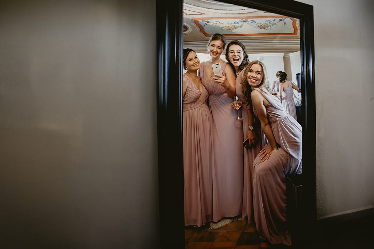 Destination wedding al Relais Sant'Uffizio. Preparazione della sposa. Damigelle si guardano allo specchio.