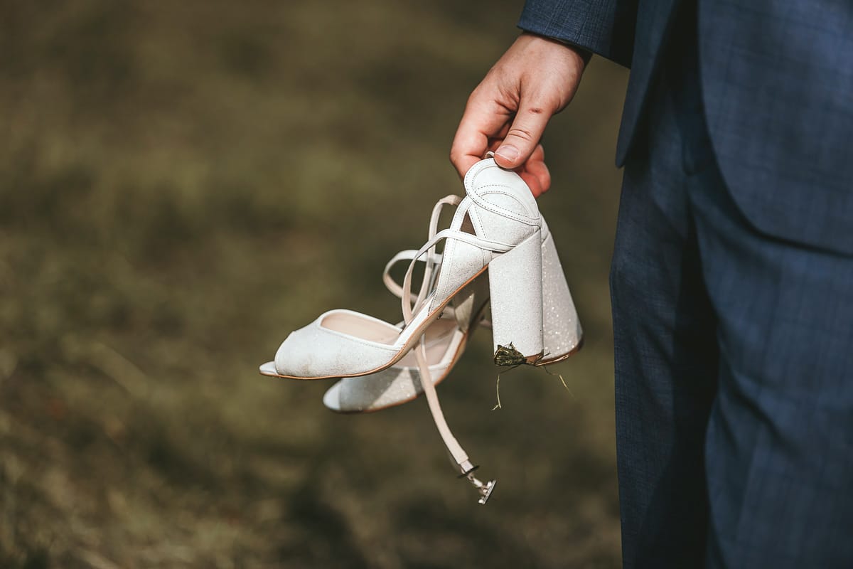 Destination wedding al Relais Sant'Uffizio. Sessione fotografica di coppia. Sposo ha in mano le scarpe della sposa.