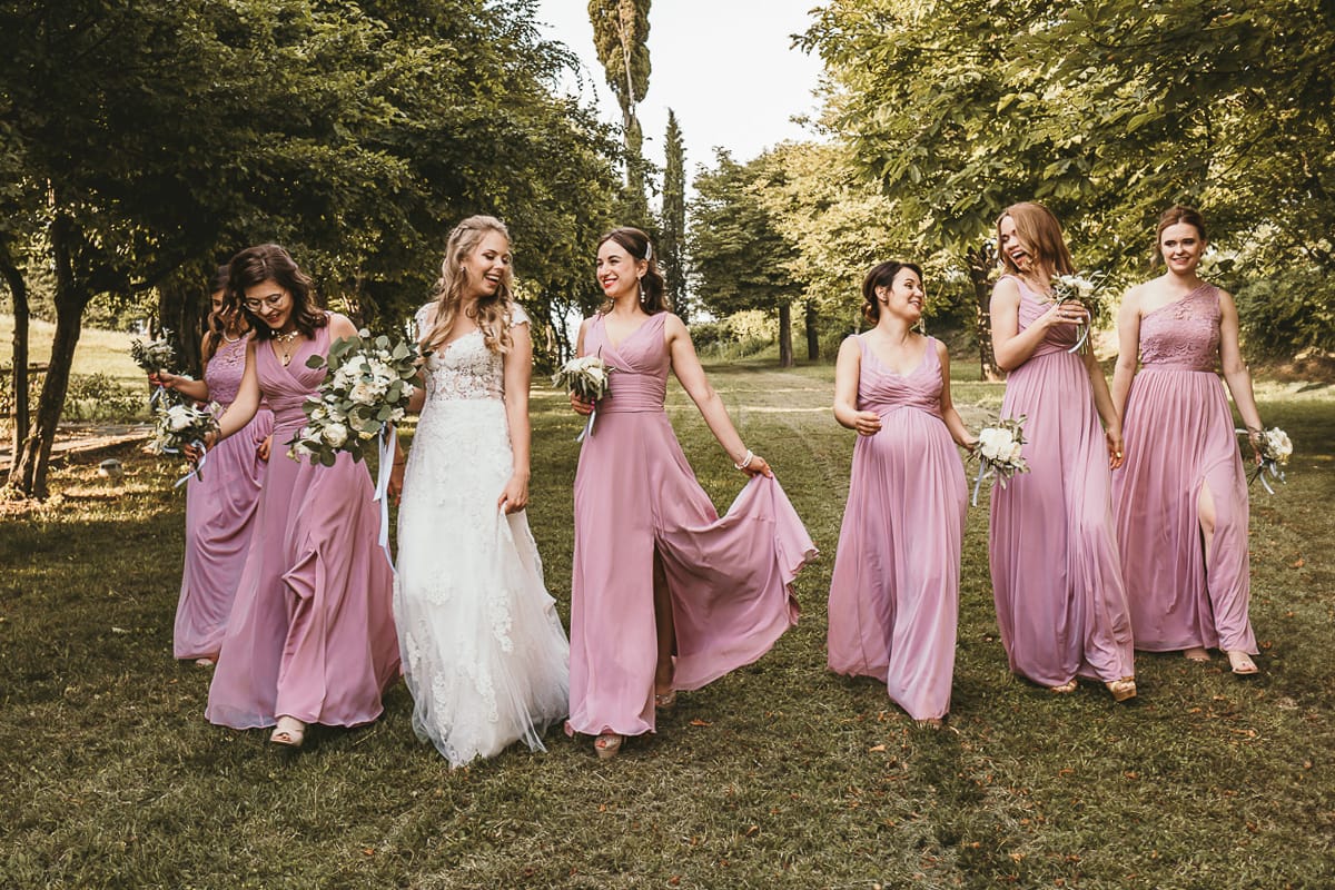 Destination wedding al Relais Sant'Uffizio. Fotografia di gruppo. Sposa cammina con le damigelle.