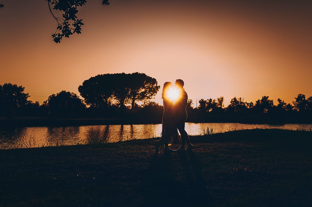 Servizio fotografico di coppia nella Laguna del Delta del Po al tramonto. Silhouette e sole tra la coppia.