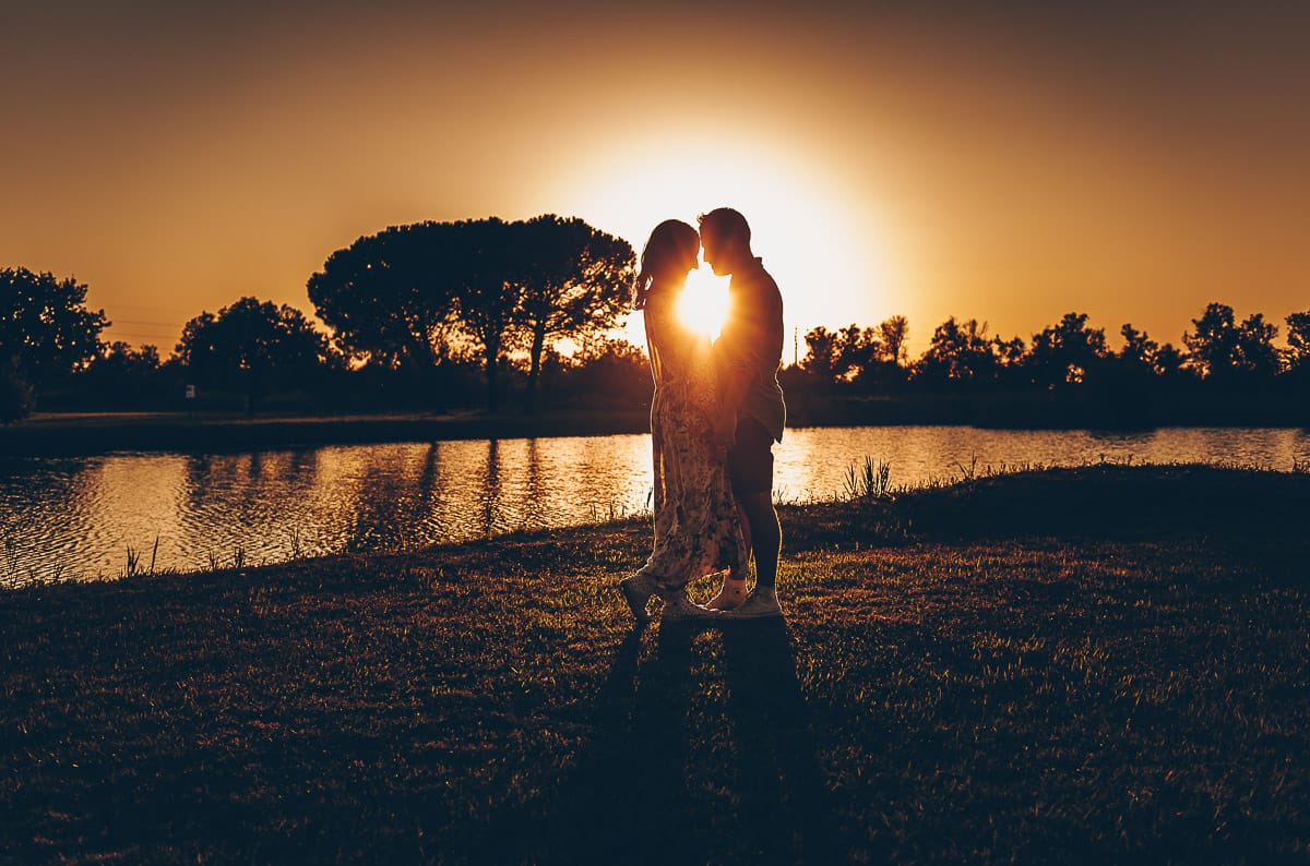 Servizio fotografico di coppia nella Laguna del Delta del Po al tramonto. Silhouette e sole tra la coppia.