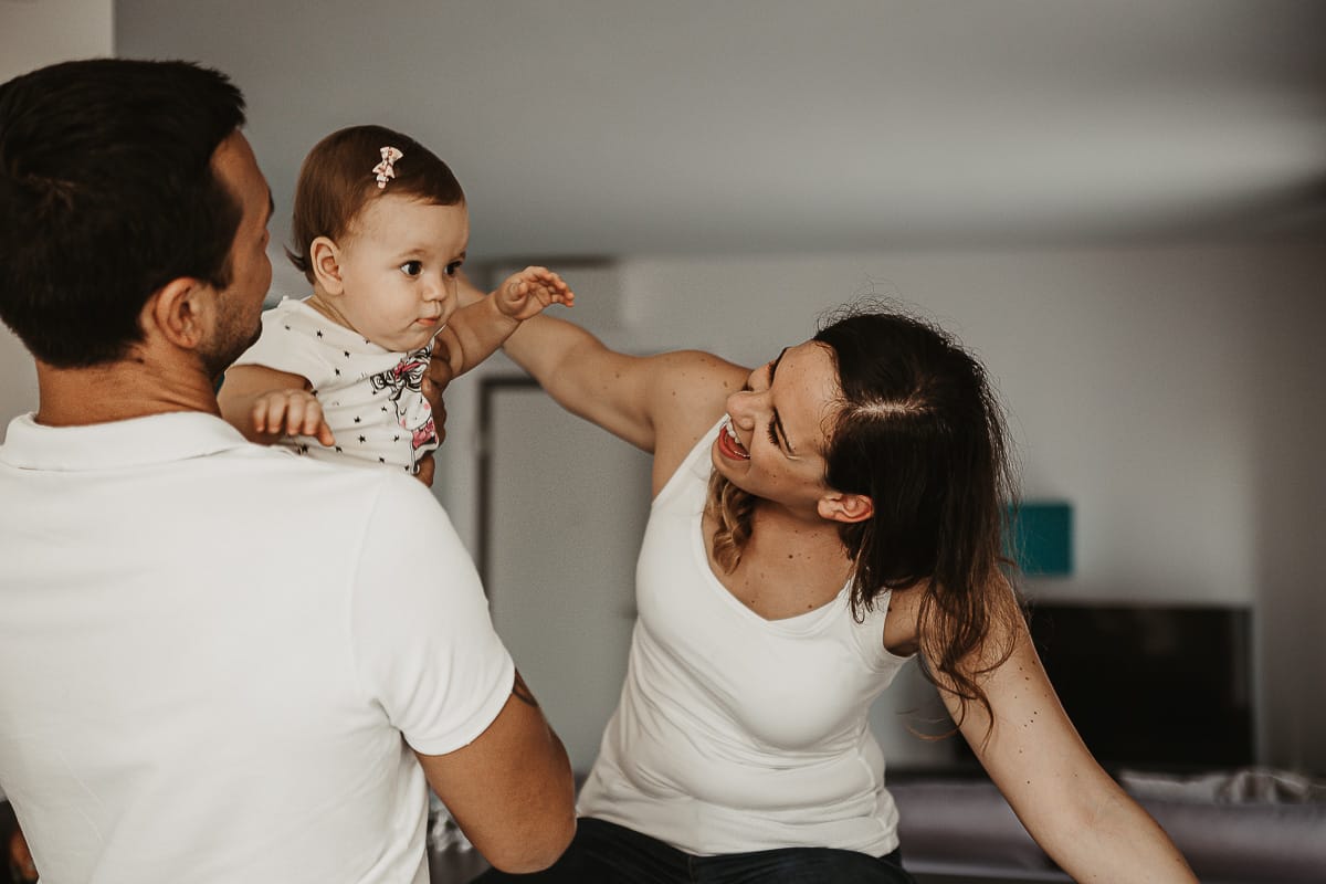 Fotografia di famiglia a Chieri. La piccola Aurora tra le braccia dei genitori sul bancone della cucina