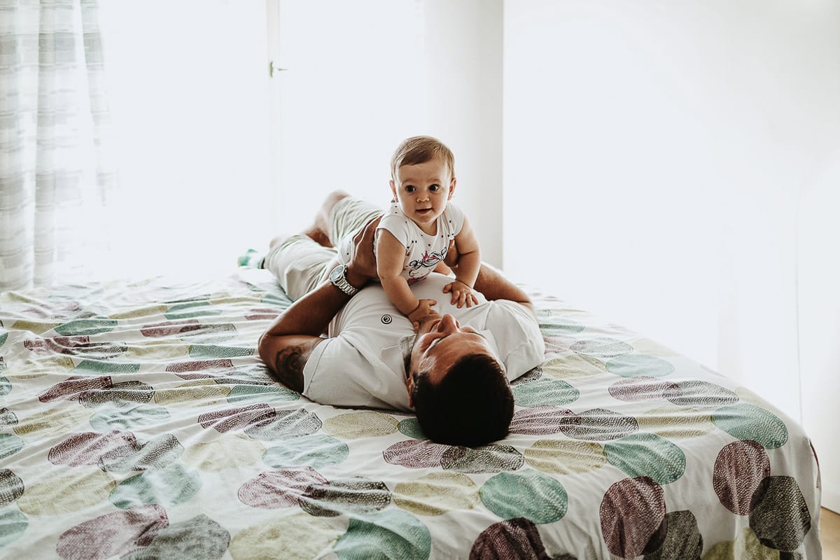Fotografia di famiglia a Chieri. La piccola Aurora sul lettone sulla pancia del papà
