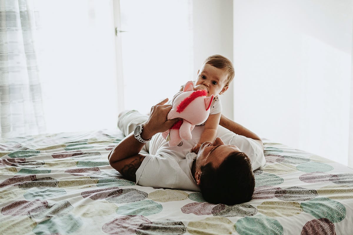 Fotografia di famiglia a Chieri. La piccola Aurora sul lettone sulla pancia del papà