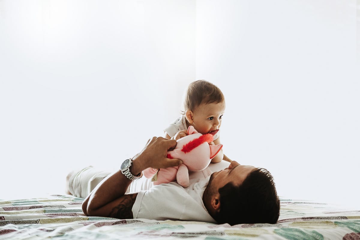 Fotografia di famiglia a Chieri. La piccola Aurora sul lettone sulla pancia del papà