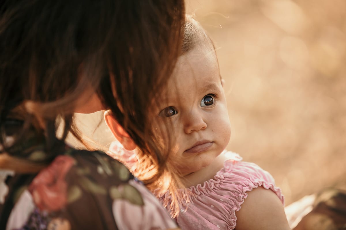 Fotografia di famiglia a Chieri. Ritratti spontanei in esterno nelle colline intorno alla città, al tramonto. Primo piano della bambina