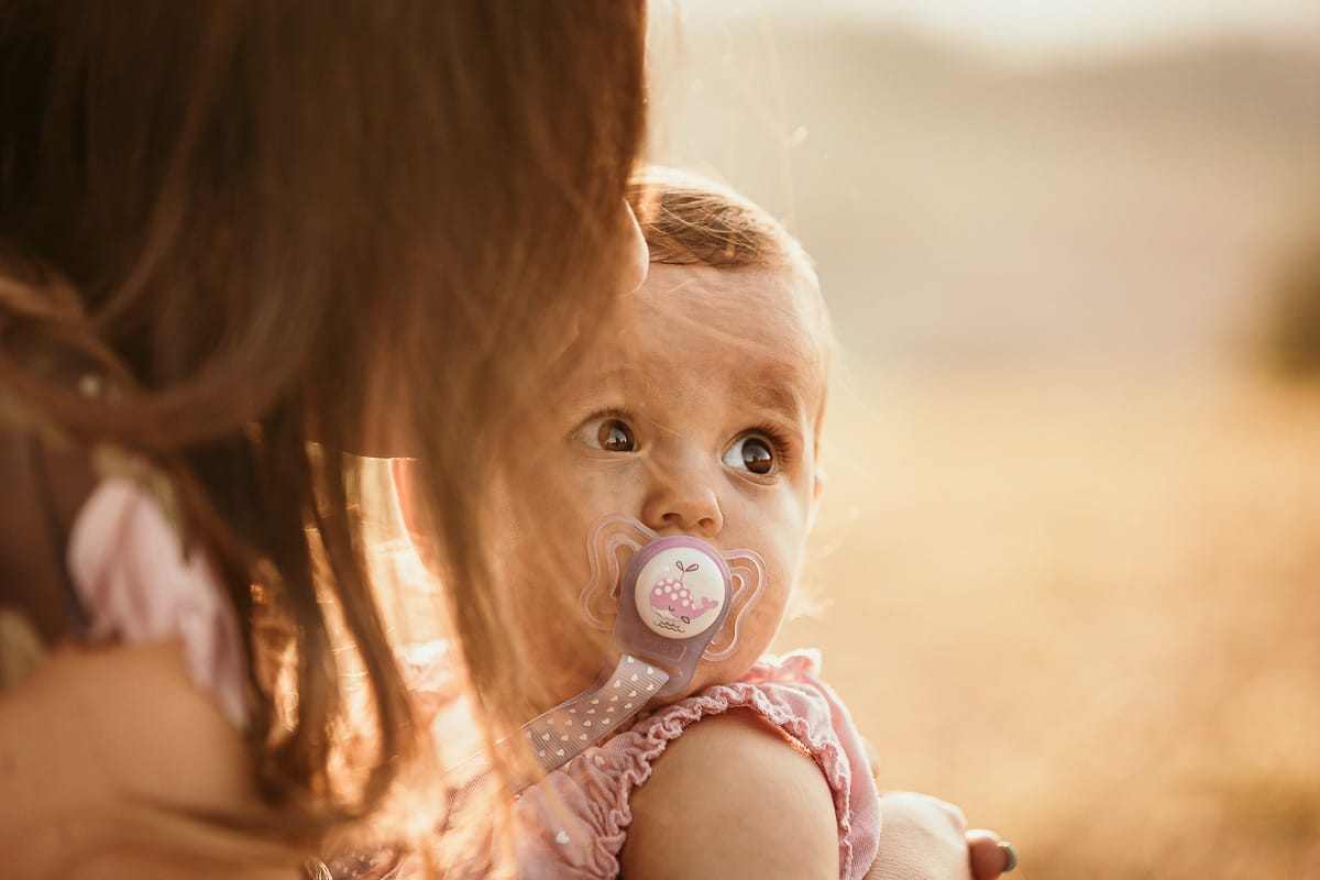 Fotografia di famiglia a Chieri. Ritratti spontanei in esterno nelle colline intorno alla città, al tramonto.Primo piano della bambina