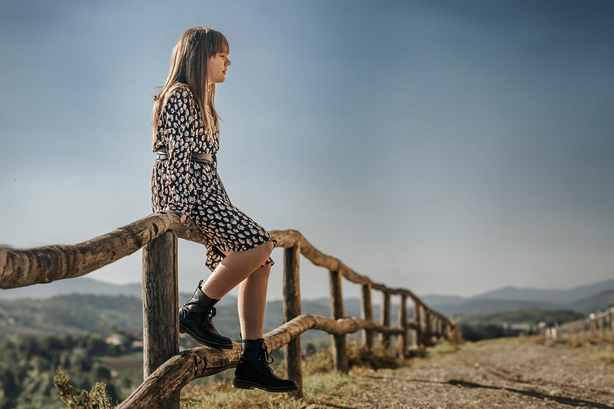 Servizio fotografico di famiglia autunnale in Monferrato. Figlia seduta su di una staccionata di legno