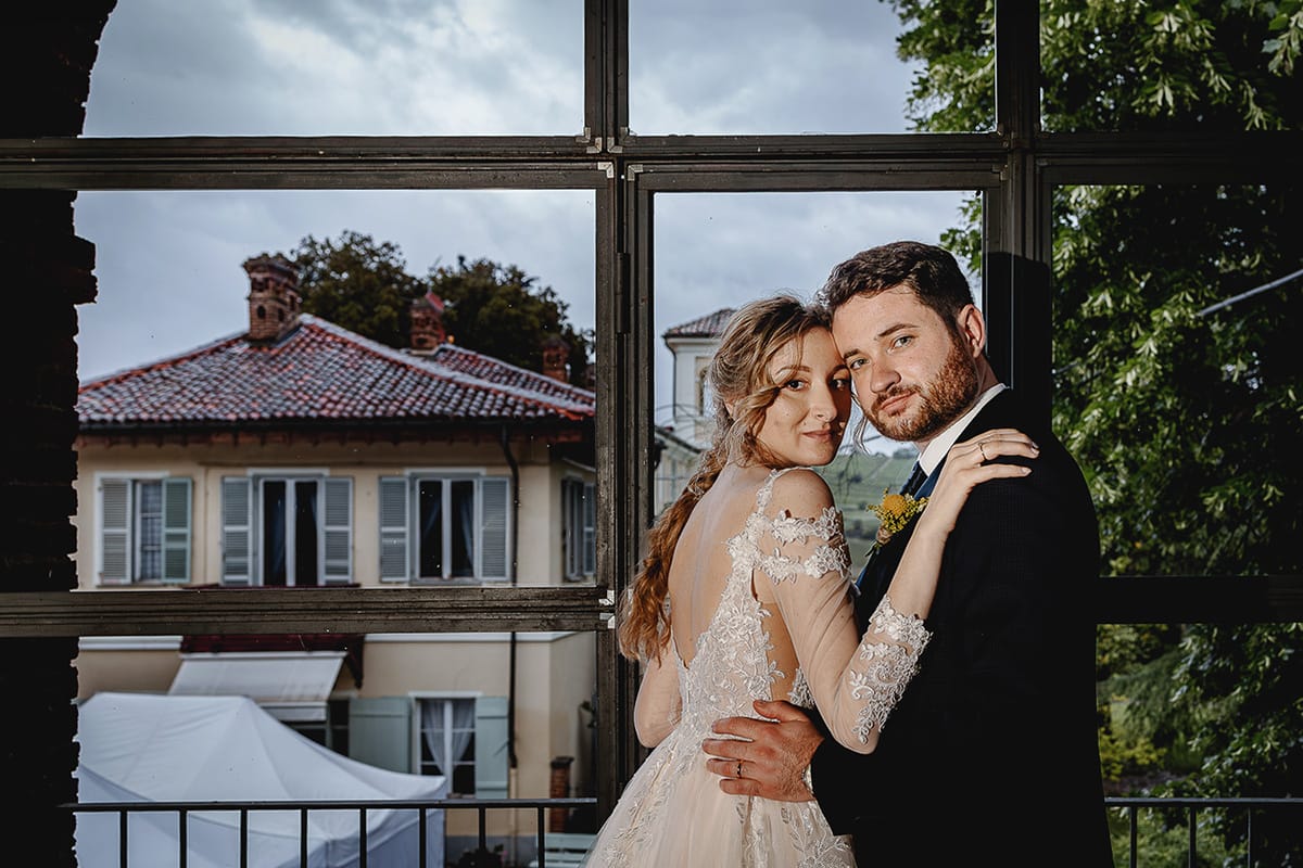 Matrimonio sotto la pioggia a Tenuta Tamburnin di Castelnuovo Don Bosco. Ritratto degli sposi alla finestra