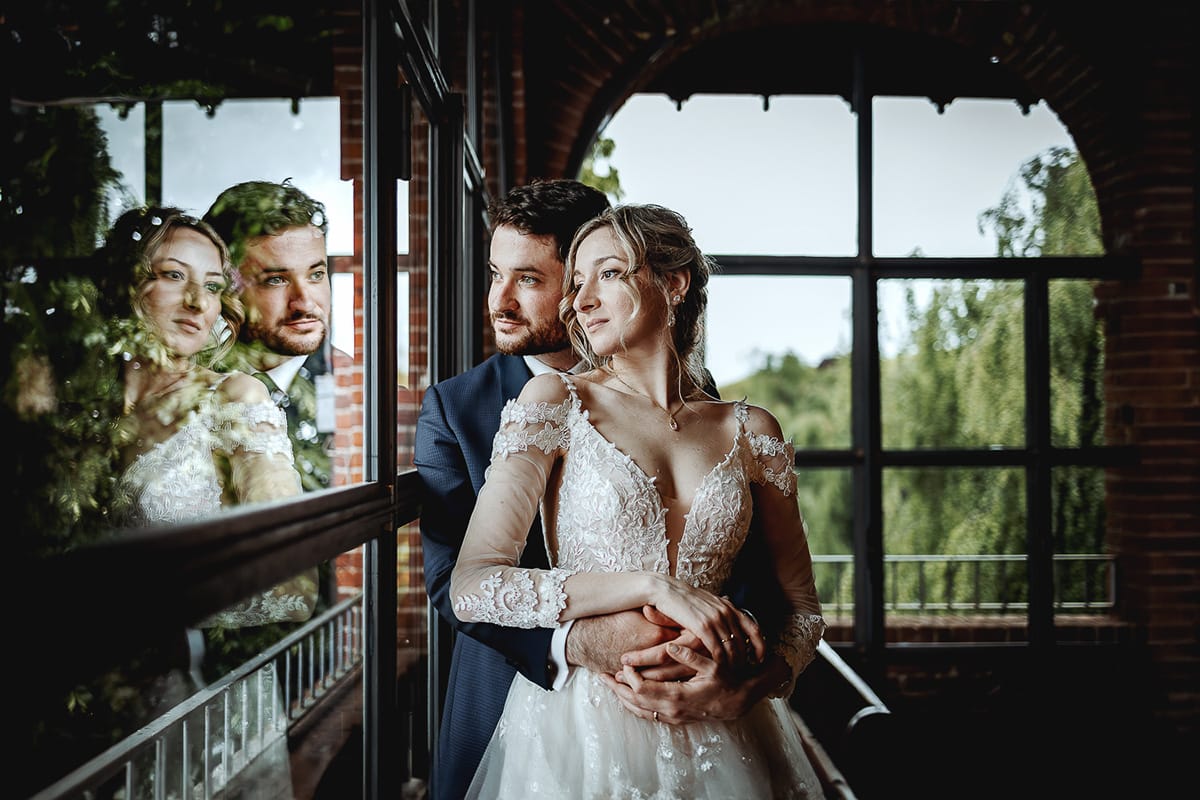 Matrimonio sotto la pioggia a Tenuta Tamburnin di Castelnuovo Don Bosco. Ritratto degli sposi alla finestra riflessi