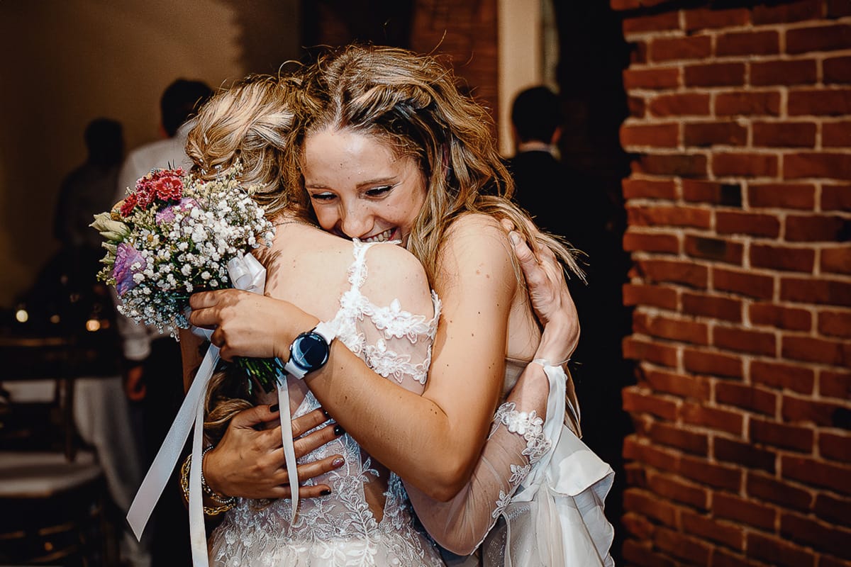 Matrimonio sotto la pioggia a Tenuta Tamburnin di Castelnuovo Don Bosco. Cena.lancio del bouquet sposa abbraccia la ragazza che ha preso il bouquet