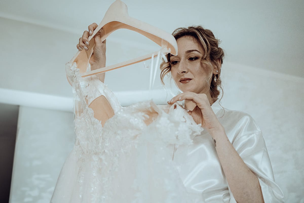 Matrimonio sotto la pioggia a Cambiano. preparazione della sposa.sposa prende l'abito dalla gruccia