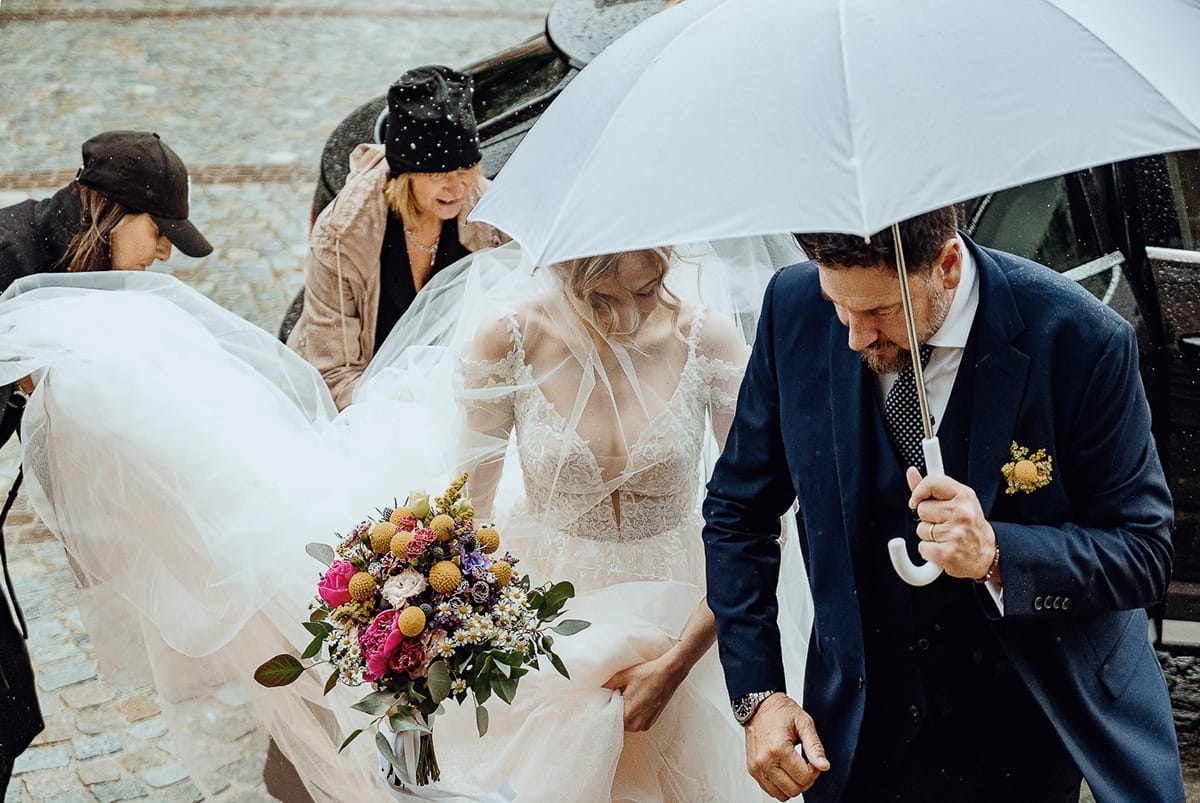 Matrimonio sotto la pioggia a Cambiano. Cerimonia. Sposa esce dall'auto. Padre tiene l'ombrello