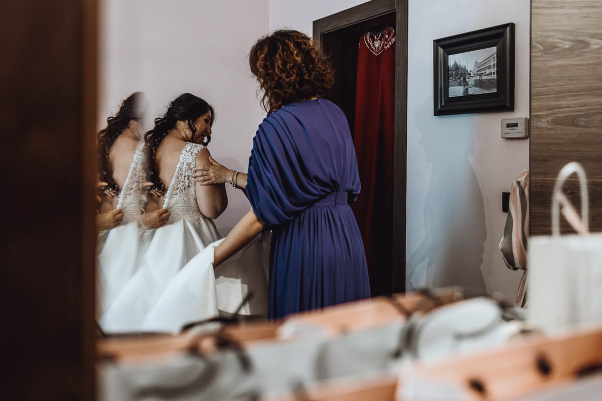 Matrimonio a Riva presso Chieri, preparazione della sposa. vestizione della sposa riflessa nello specchio del comò.
