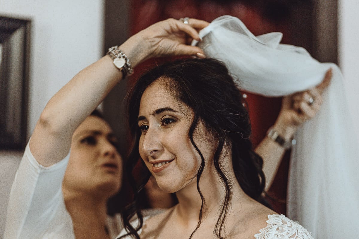 Matrimonio a Riva presso Chieri, preparazione della sposa. La parrucchiera mette il velo alla sposa.
