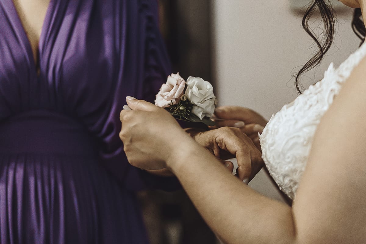 Matrimonio a Riva presso Chieri, preparazione della sposa. la sposa mette il corsage alla testimone.