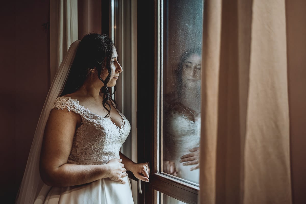 Matrimonio a Riva presso Chieri, preparazione della sposa.Ritratto della sposa alla finestra.