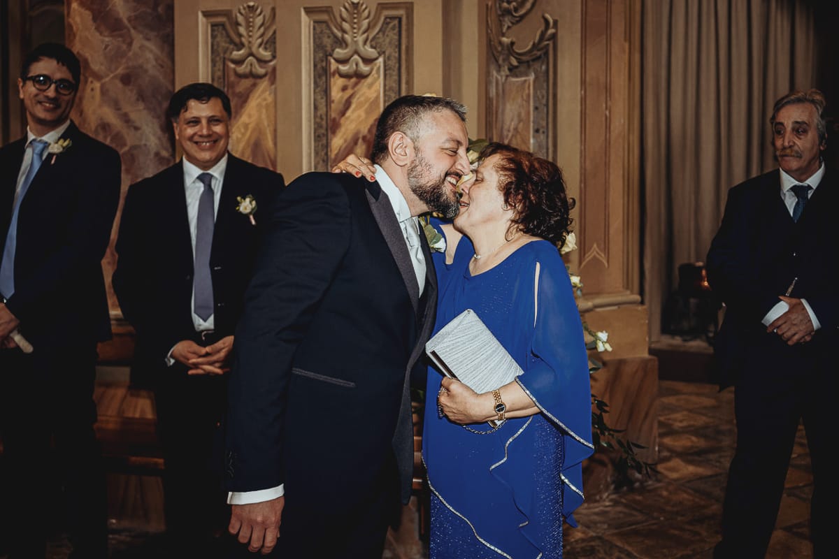 Matrimonio a Riva presso Chieri. Cerimonia. Sposo in chiesa bacia la madre.