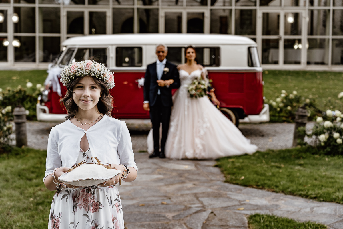 Castello dei Solaro, matrimonio di Noemi e Pietro. Cerimonia. Damigella e dietro sposa con il padre davanti al Van Wolkswagen rosso.