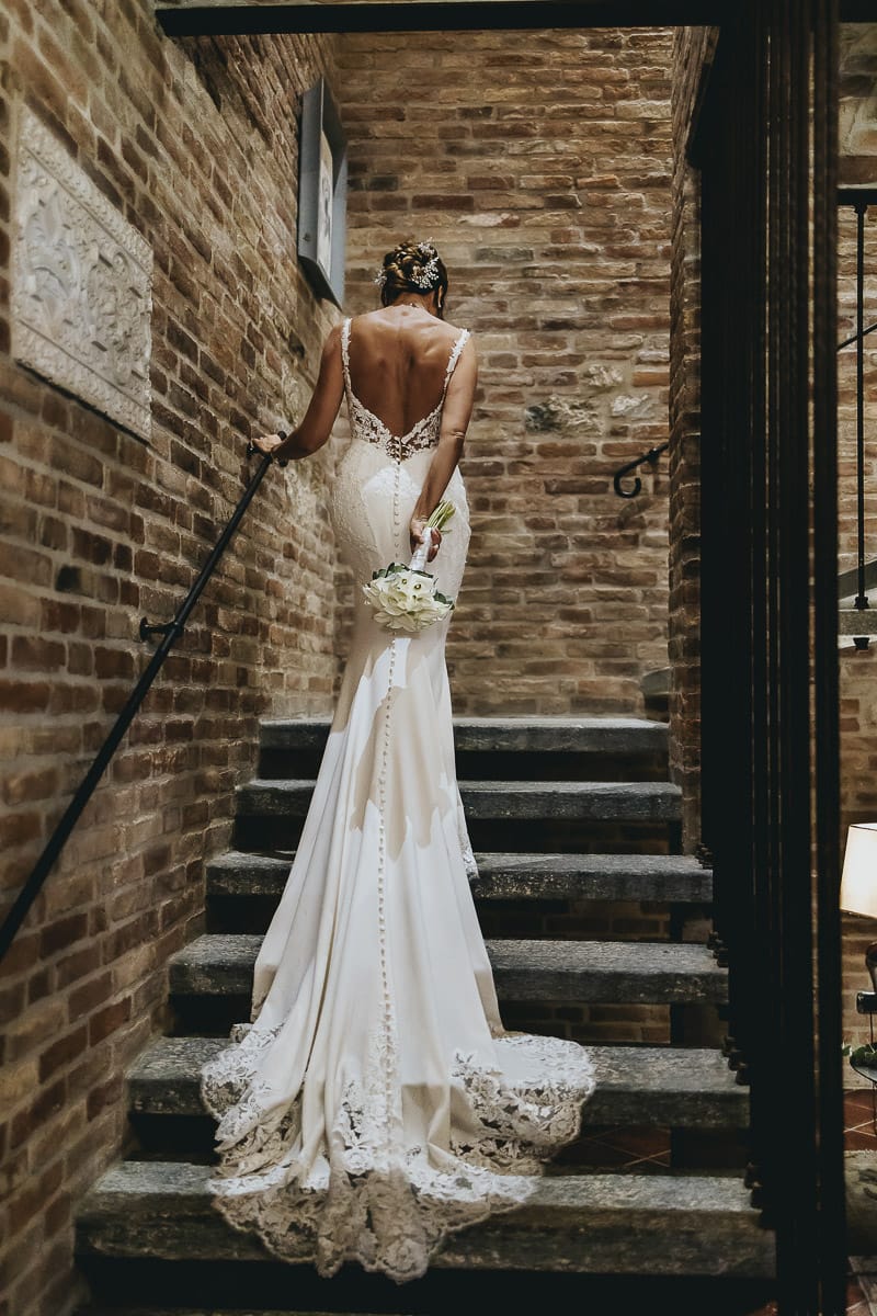 Matrimonio a "La Madernassa" nelle Langhe sotto la pioggia. Ritratto della sposa di dietro sulla scala.