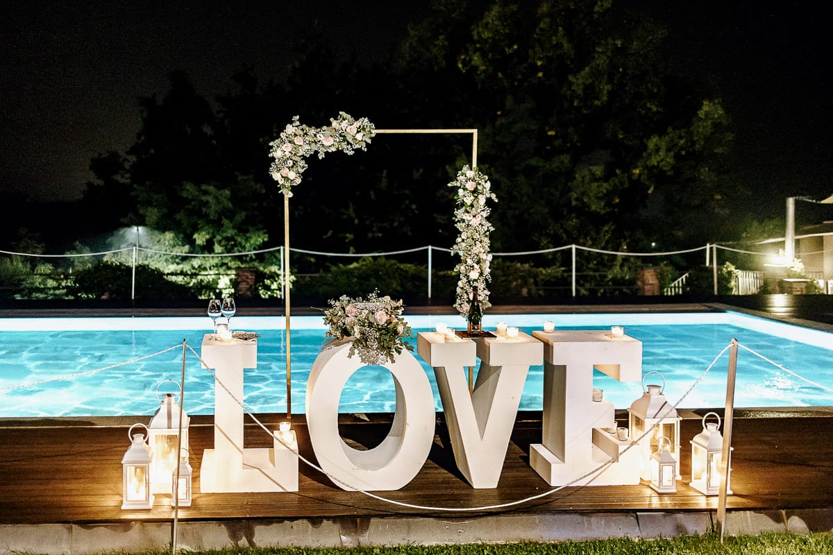 Matrimonio a "La Madernassa" nelle Langhe sotto la pioggia. Taglio torta. Allestimento luminoso, fiori e scritta LOVE.