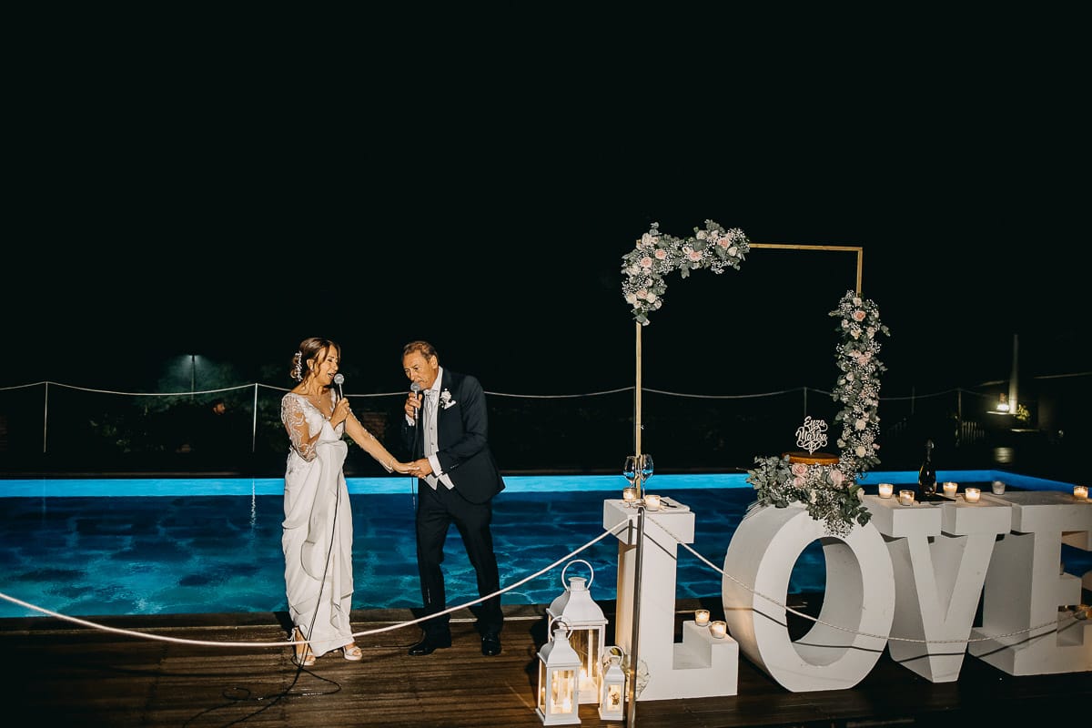 Matrimonio a "La Madernassa" nelle Langhe sotto la pioggia. Taglio torta. Allestimento luminoso, fiori e scritta LOVE.