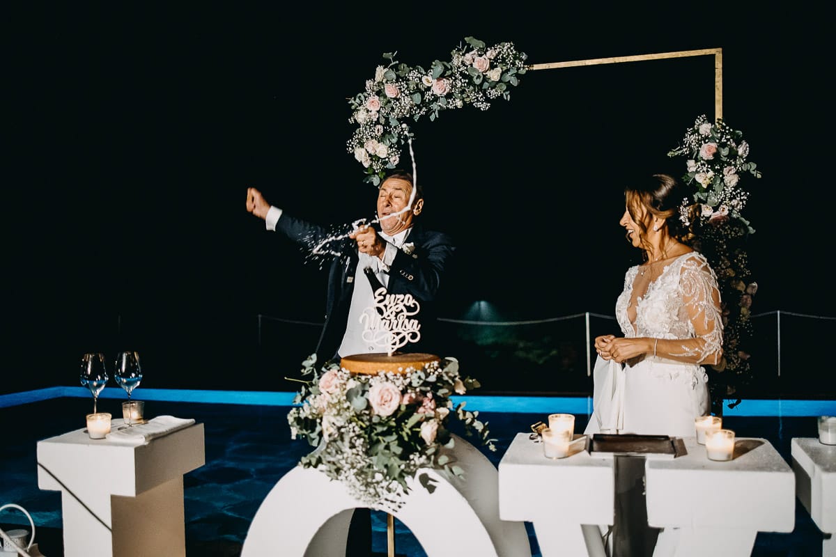 Matrimonio a "La Madernassa" nelle Langhe sotto la pioggia. Taglio torta. Allestimento luminoso, fiori e scritta LOVE.
