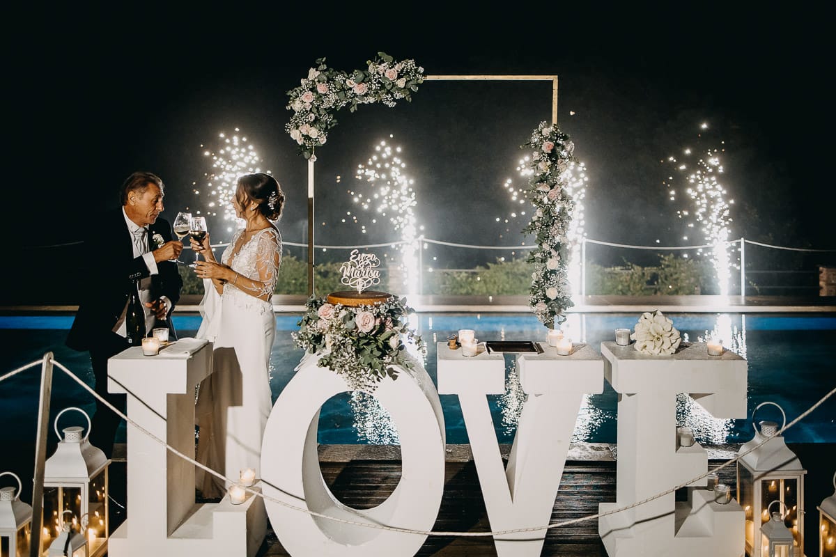 Matrimonio a "La Madernassa" nelle Langhe sotto la pioggia. Taglio torta. Allestimento luminoso, fiori e scritta LOVE.