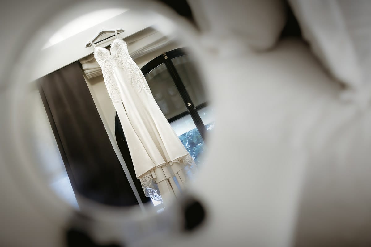 Matrimonio a "La Madernassa" nelle Langhe sotto la pioggia. Preparazione della sposa. Abito riflesso in uno specchio.