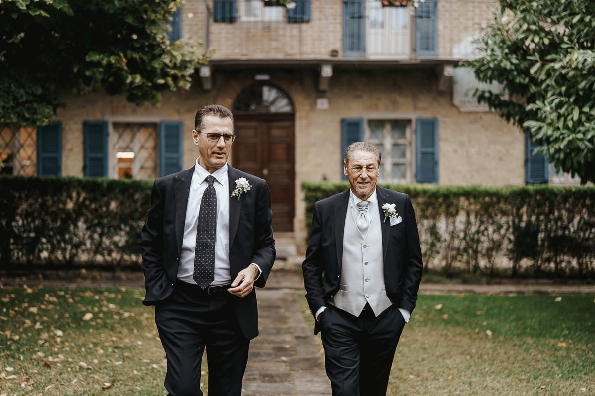 Matrimonio a "La Madernassa" nelle Langhe sotto la pioggia. preparazione dello sposo. sposo e testimone camminano.
