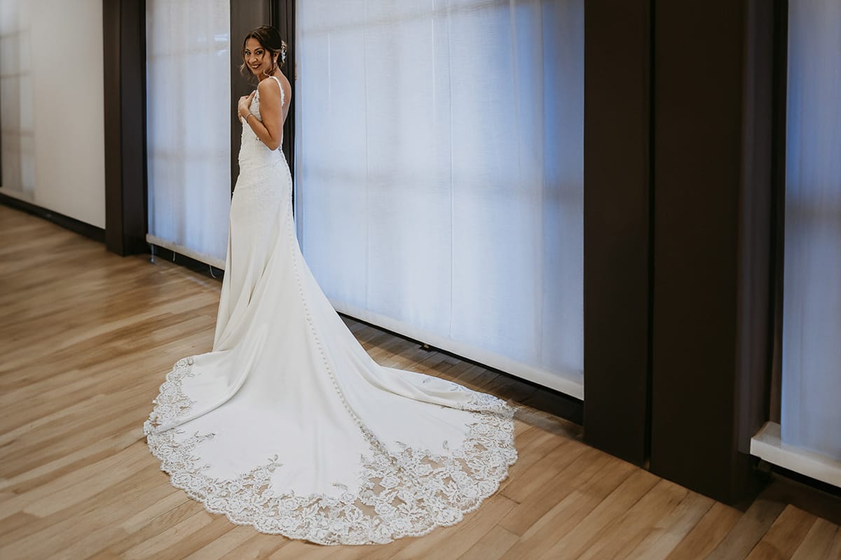 Matrimonio a "La Madernassa" nelle Langhe sotto la pioggia. Preparazione della sposa. Ritratto della sposa da dietro con il vestito con una grande coda di pizzo.