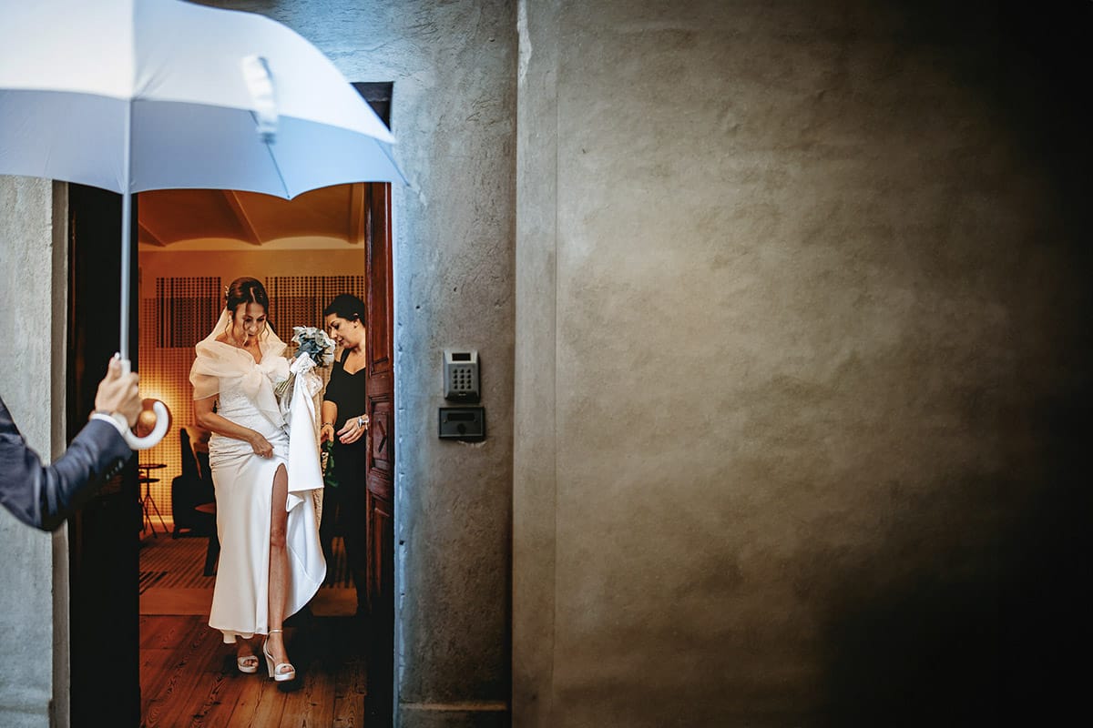 Matrimonio a "La Madernassa" nelle Langhe sotto la pioggia. Preparazione della sposa. Ritratto della sposa mentre sta per uscire ed affrontare la pioggia.
