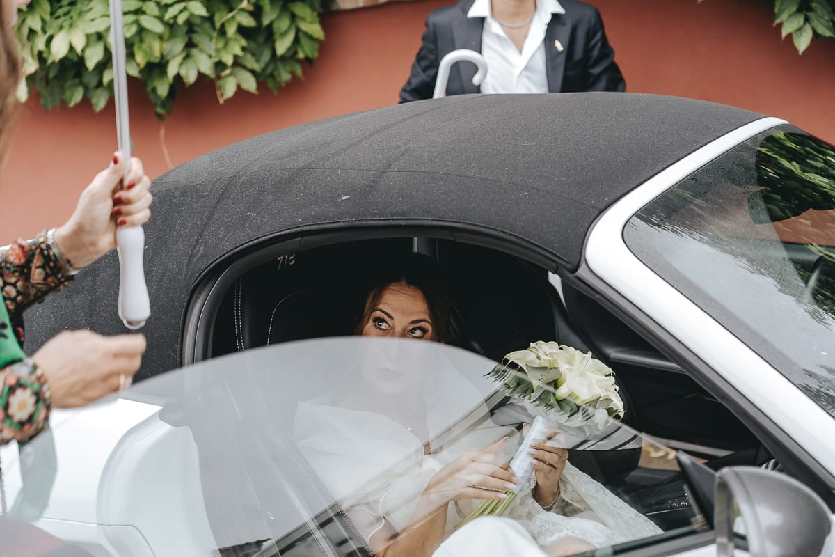 Matrimonio a "La Madernassa" nelle Langhe sotto la pioggia. Cerimonia. Sposa in auto.