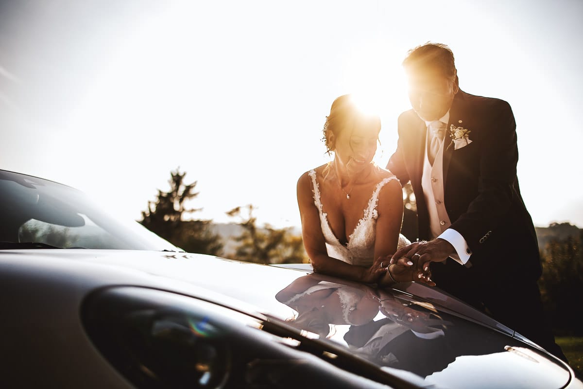 Post wedding a La Madernassa. Sposi all'esterno vicino alla Porsche bianca. tramonto. Riflessi nell'auto