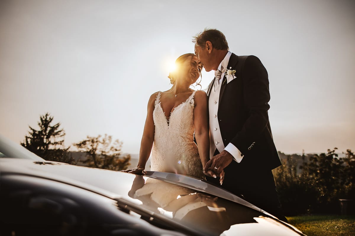 Post wedding a La Madernassa. Sposi all'esterno vicino alla Porsche bianca. Tramonto riflessi nell'auto