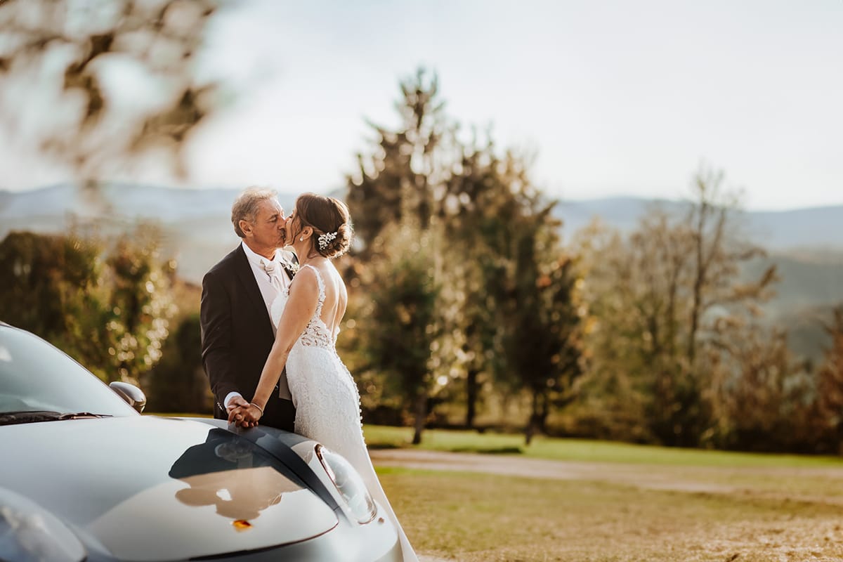 Post wedding a La Madernassa. Sposi all'esterno vicino alla Porsche bianca. Bacio