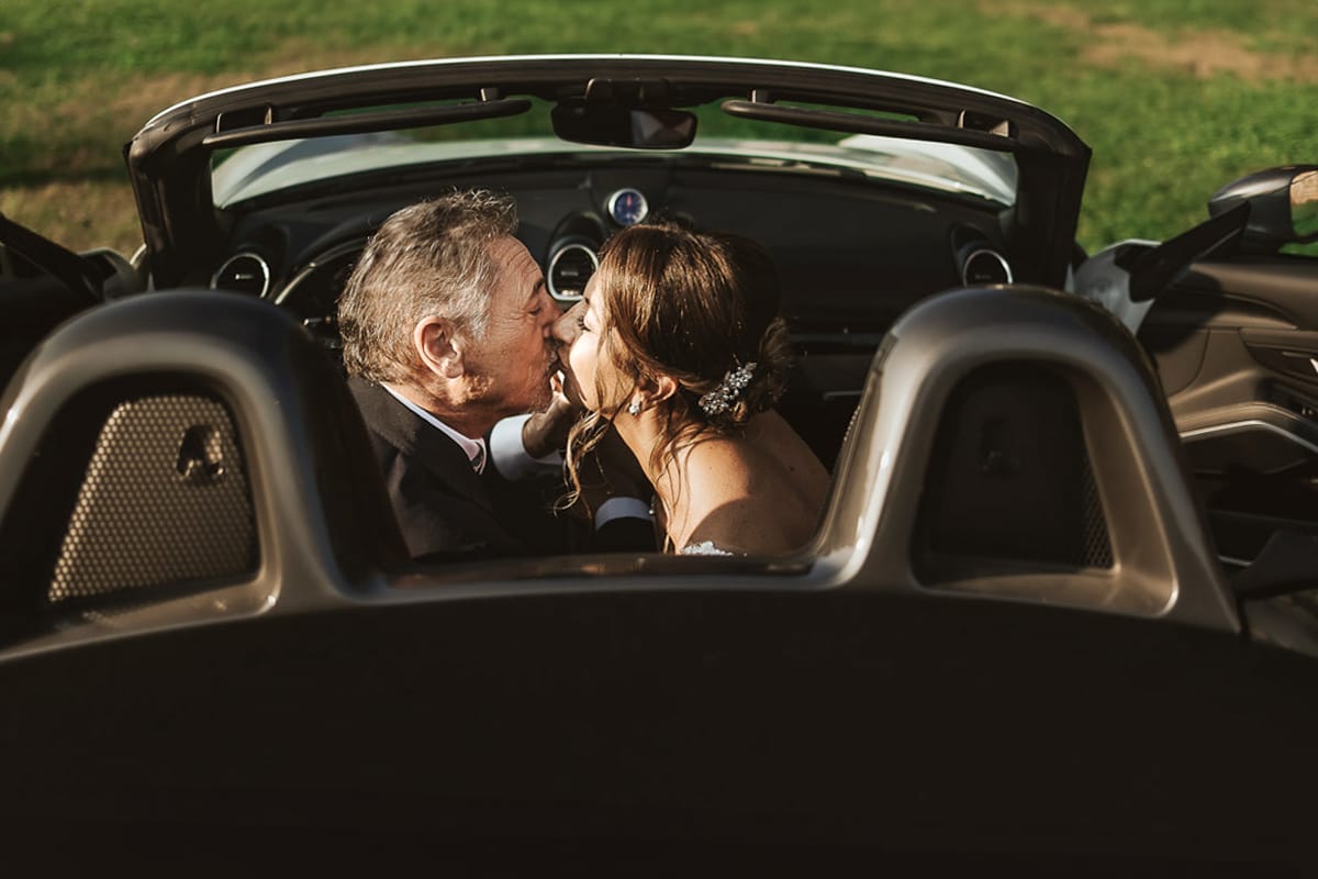 Post wedding a La Madernassa. Sposi all'esterno dentro la Porsche bianca. Bacio