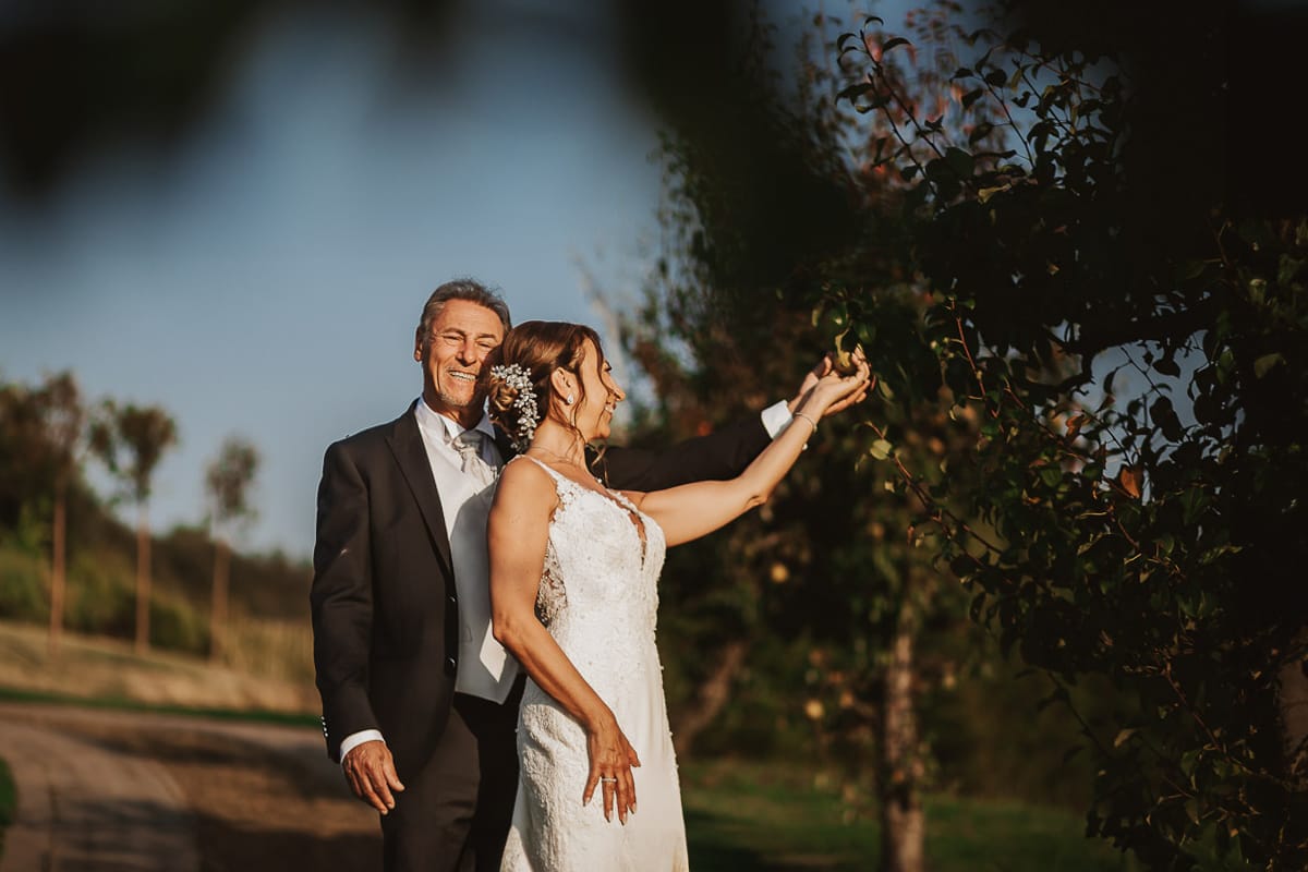 Post wedding a La Madernassa. Sposi passeggiano tra i peri che danno il nome alla location e toccano le pere