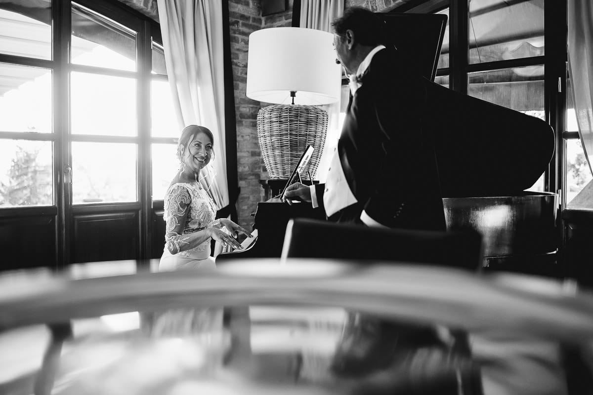 Post wedding a La Madernassa. Sposa suona il pianoforte. sposo ascolta in piedi accanto al pianoforte. Bianco e nero