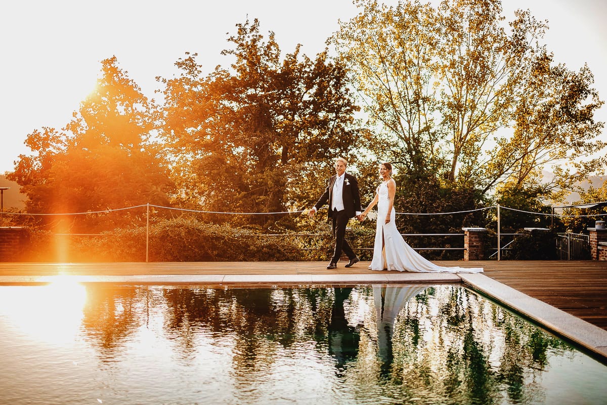 Post wedding a La Madernassa. Sposi passeggiano a bordo piscina al tramonto.
