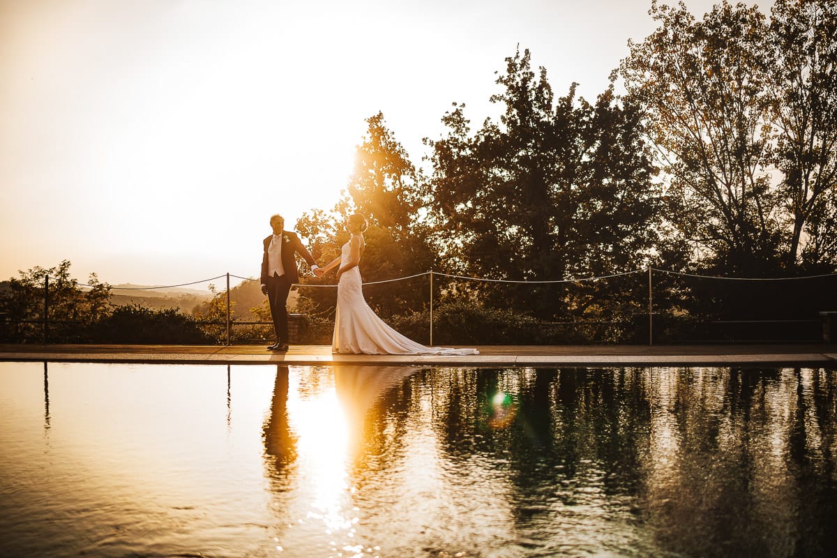 Post wedding a La Madernassa. Sposi passeggiano a bordo piscina al tramonto.