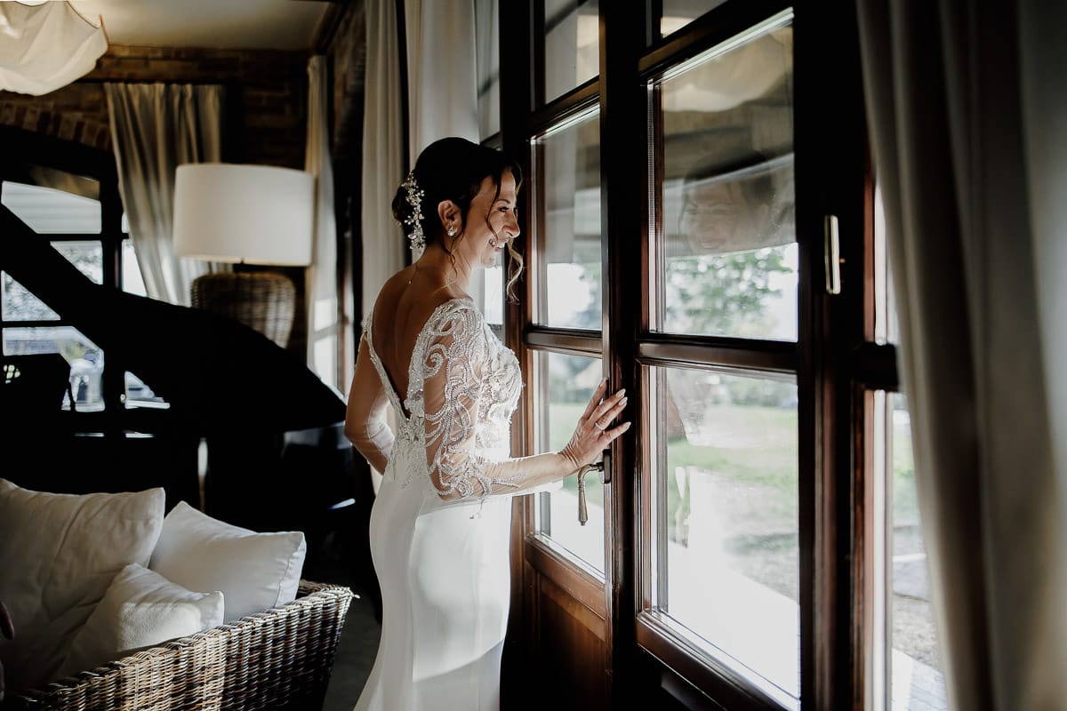 Post wedding a La Madernassa. Sposa guarda fuori da una vetrata