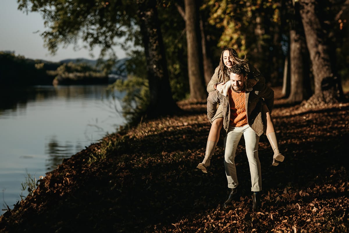 Prewedding a Torino, sul lungo Po al tramonto. La coppia gioca. la ragazza salta sulle spalle del ragazzo.