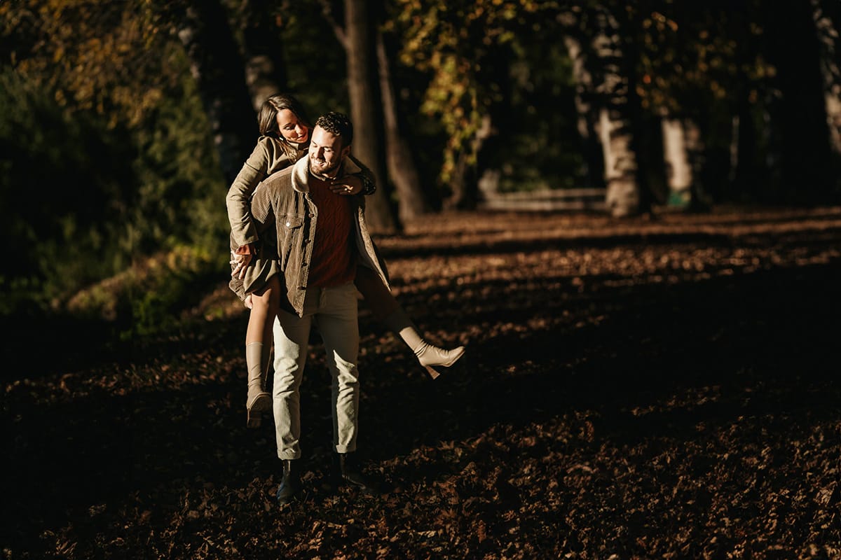 Prewedding a Torino, sul lungo Po al tramonto. La coppia gioca. la ragazza salta sulle spalle del ragazzo.