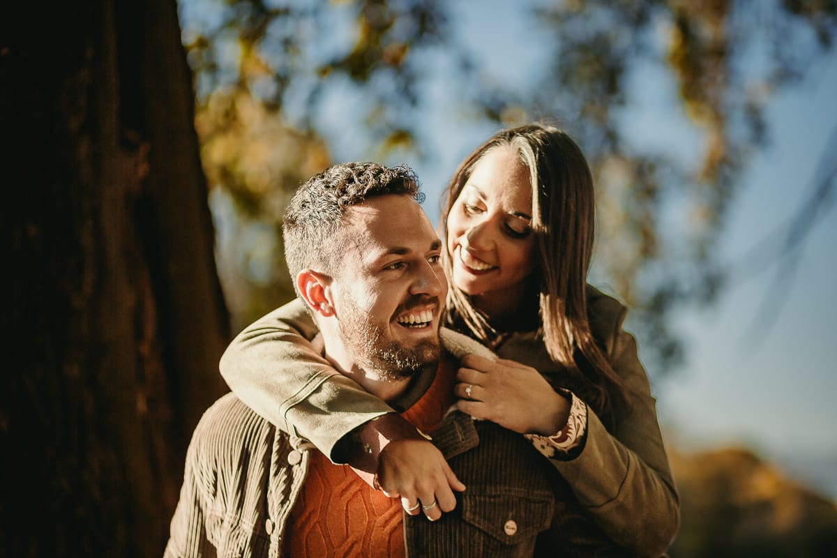 Prewedding a Torino, sul lungo Po al tramonto. La coppia gioca. la ragazza salta sulle spalle del ragazzo.