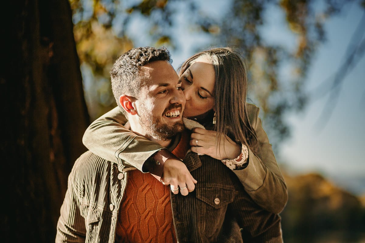 Prewedding a Torino, sul lungo Po al tramonto. La coppia gioca. la ragazza salta sulle spalle del ragazzo.